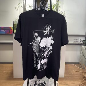 Black T-shirt hanging on rack with white abstract graphic of shapes and figures on front